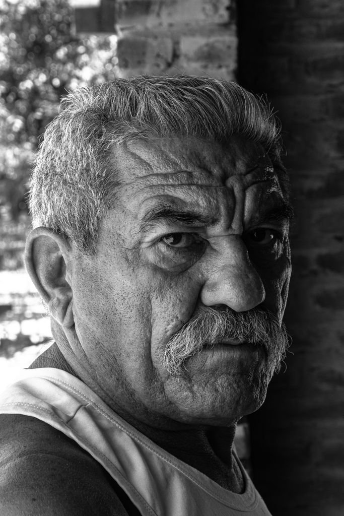 Black and white portrait of an elderly man with a mustache, highlighting his serious expression.